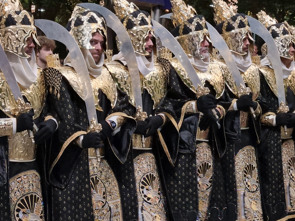 Participantes de Moros y Cristianos de Murcia con espadas curvas y trajes dorados