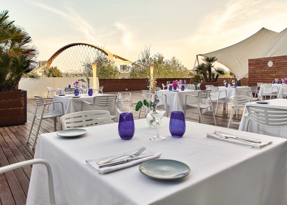 Terraza del restaurante Celebris con vistas al Puente del Tercer Milenio durante una cena de verano.