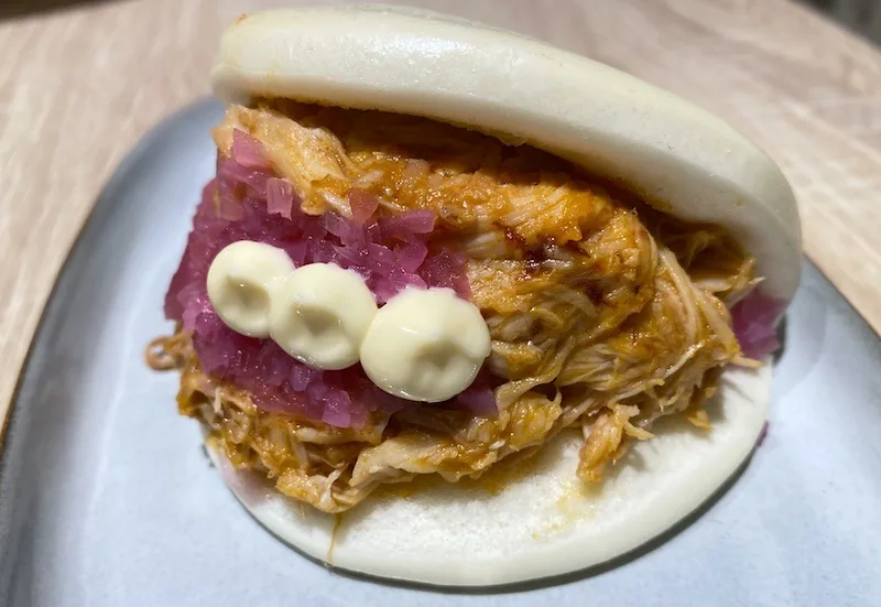 Pan bao relleno de pollo al chilindrón con cebolla encurtida y salsa

