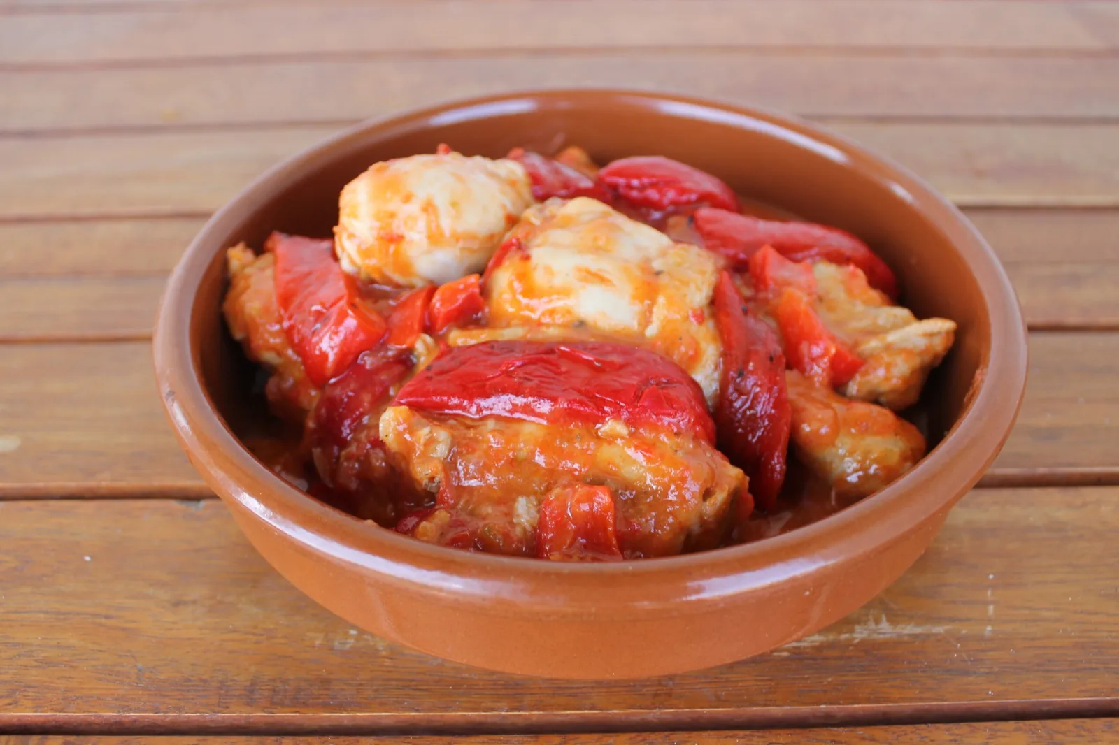 Pollo al chilindrón con pimientos rojos servido en una cazuela de barro