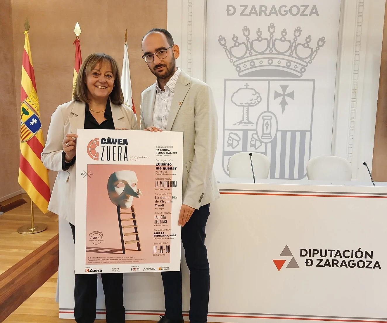 Dos representantes institucionales sostienen el cartel del Festival Cávea Zuera 2026 durante su presentación.
